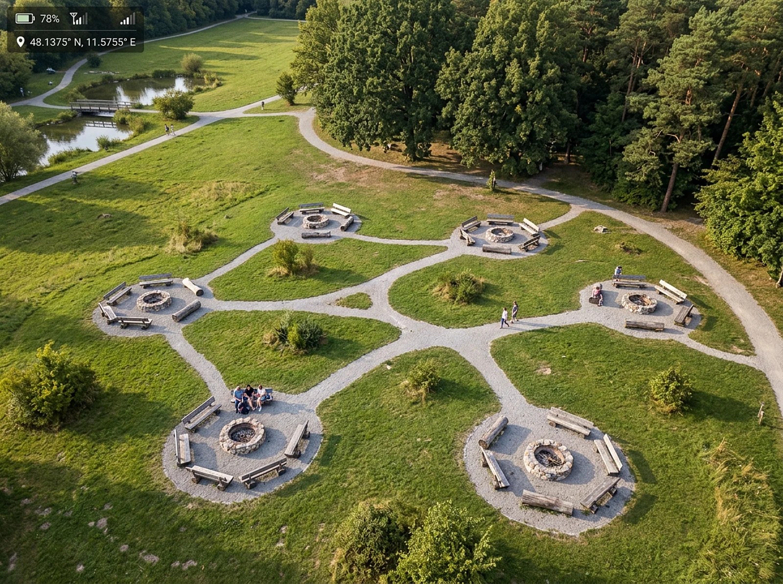 Eine Luftaufnahme zeigt mehrere Feuerstellen mit Sitzbänken, Wegen, Wiesen und Teich – ein Ort fürs Grillen in Bonn.